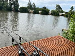 a boat with a fishing rod on the side of a river at Anglers Rest, with Hot Tub and Private Fishing Peg in Tattershall