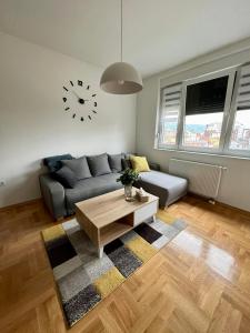 a living room with a couch and a clock on the wall at Apartman IRIS 3 in Banja Luka