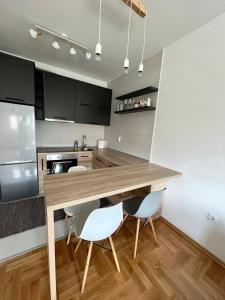 a kitchen with a wooden table and white chairs at Apartman IRIS 3 in Banja Luka