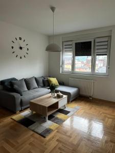 a living room with a couch and a clock on the wall at Apartman IRIS 3 in Banja Luka