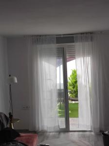 a room with white curtains and a sliding glass door at Casa Rural Maestros in Albanchez de Úbeda