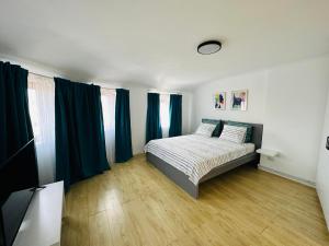 a bedroom with a bed with blue curtains and wooden floors at Turqoise Central Apartaments in Bucharest
