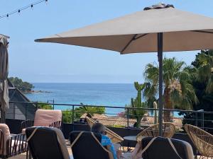a patio with chairs and an umbrella and the ocean at Les Alcyons in Le Lavandou