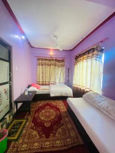 2 camas en una habitación con paredes moradas y alfombra en Himchuli Guest House, en Bandipur