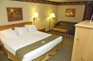 a hotel room with a large bed and a couch at Pellston Lodge in Pellston