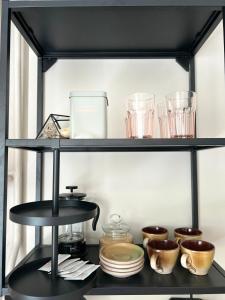 a black shelf with dishes and glasses on it at Skandi Appartments in Saldus city center in Saldus