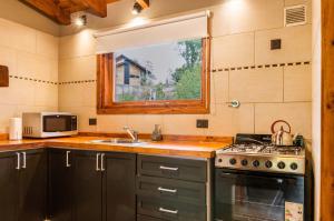 a kitchen with a sink and a stove and a window at BOG Melania - casa en el bosque in Villa La Angostura