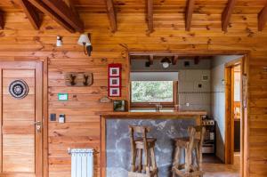 a kitchen with wooden walls and a bar with stools at BOG Melania - casa en el bosque in Villa La Angostura