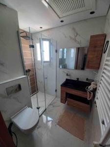 een badkamer met een douche, een toilet en een wastafel bij Lilia's house Al Kantaoui in Sousse