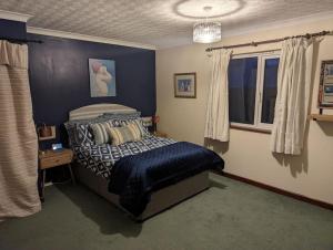 a blue bedroom with a bed and a window at Idyllic, Luxurious Seaside Flat for 4. in Borth