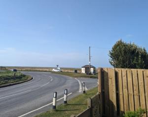 a road with a fence on the side of the road at Idyllic, Luxurious Seaside Flat for 4. in Borth