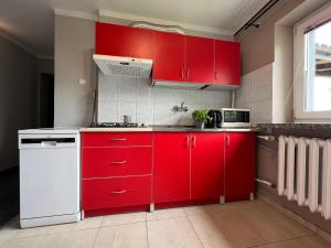 a kitchen with red cabinets and a white refrigerator at Apartamenty Romano in Rzeszów