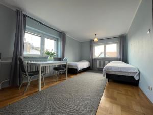a room with two beds and a table and chairs at Apartamenty Romano in Rzeszów
