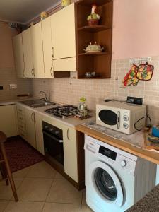 eine Küche mit einer Waschmaschine und einer Mikrowelle in der Unterkunft Appartamento per le vacanze ,, Villa Miky,, in Pairola