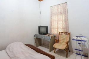 Schlafzimmer mit einem Bett, einem TV und einem Stuhl in der Unterkunft Mountain View Homestay in Tomohon