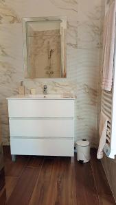 een badkamer met een witte wastafel en een spiegel bij Agréable chambre dans le maquis in Bonifacio