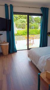 a bedroom with a bed and a sliding glass door at Agréable chambre dans le maquis in Bonifacio