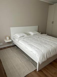 uma cama branca com 2 almofadas num quarto em Skandi Appartments in Saldus city center em Saldus