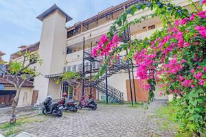 a group of motorcycles parked outside of a building with pink flowers at Guest House Simalem in Legian