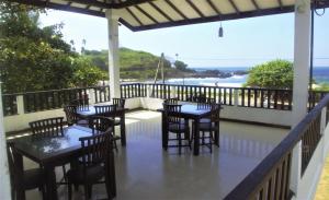 a restaurant with tables and chairs on a balcony with the ocean at Thalalla Ocean View in Dickwella