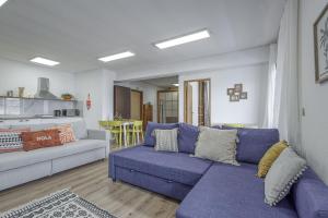a living room with a blue couch and a kitchen at Travel & Live Fernão Magalhães in Porto