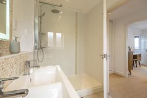 La salle de bains blanche est pourvue d'une douche et d'un lavabo. dans l'établissement Sherborne House, à Wells-next-the-Sea