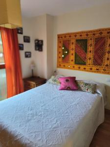 una camera da letto con un letto bianco e cuscini rosa di Dúplex con jardín en Pirineos, totalmente equipado a Villanúa