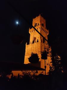 Una torre de reloj por la noche con la luna al fondo en 4 Assi, en Pitigliano