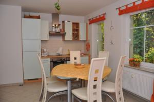 - une cuisine avec une table en bois et des chaises blanches dans l'établissement FeWo Sonnenblick, à Zinnowitz