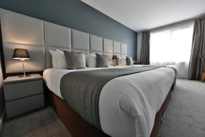 um quarto com uma cama grande e uma grande cabeceira. em Kensington Court Hotel - Earls Court em Londres
