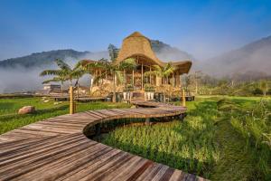 ein Holzsteg zu einem Resort mit Strohdach in der Unterkunft ภูคานาน่าน รีสอร์ท phukananan in Ban Khun Nam Nan