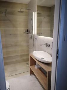 a bathroom with a white sink and a shower at Apartament Baltic Marina in Dziwnówek