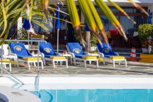 a group of blue and yellow chairs next to a pool at Sunsuites Carolina & Collection in San Agustin
