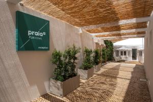 a hallway with potted plants and a sign on a wall at Praia FLH Hotels Ericeira in Ericeira
