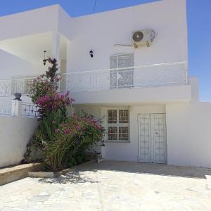 ein weißes Haus mit Blumen und einem Balkon in der Unterkunft Dar ettawfik in Tataouine