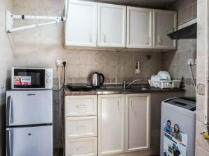 cocina con armarios blancos, fregadero y nevera en Al Ferdous Hotel Apartment, en Sharjah
