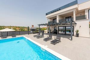 a swimming pool with chairs and a house at Vila Katarina ZadarVillas in Tinj
