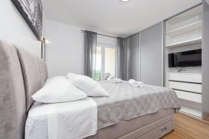 a bedroom with a bed with white sheets and a television at Vila Katarina ZadarVillas in Tinj +51 photos