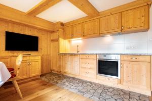 a kitchen with wooden cabinets and a flat screen tv at Mitterbruggehof Apt Enzian in Anterselva di Mezzo