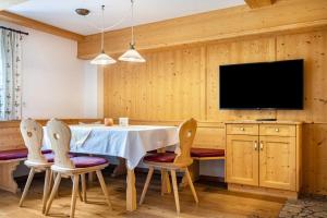 a dining room with a table and chairs and a tv at Mitterbruggehof Apt Enzian in Anterselva di Mezzo