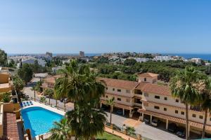 Vistas al mar de un edificio con piscina y palmeras en BLONZU SUDÁFRiCA en Benalmádena