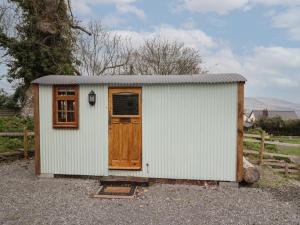 a small white shed with a wooden door at Rabbit Hill Hut in Abergavenny