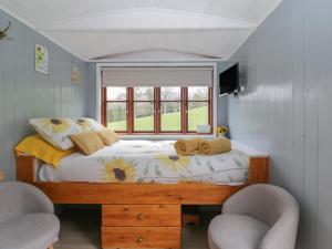 a bedroom with a bed with two chairs and a window at Rabbit Hill Hut in Abergavenny
