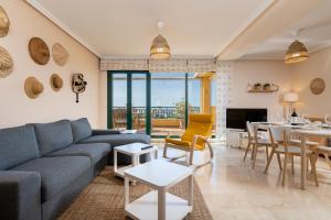 a living room with a blue couch and a dining room at BLONZU SUDÁFRiCA in Benalmádena