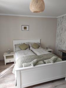 Szomolyai Vadvirág vendégház في Szomolya: غرفة نوم بيضاء مع سرير أبيض كبير مع الوسائد