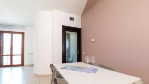una sala da pranzo bianca con tavolo e sedie bianchi di Welcomely - Xenia Boutique Tirso a Oristano