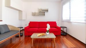 un soggiorno con divano rosso e tavolo di Welcomely - Xenia Boutique Tirso a Oristano