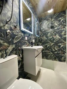 a bathroom with a sink and a leafy wallpaper at Blue Village Lux in Kolašin
