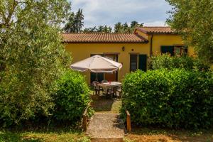 a yellow house with an umbrella and a table at Geranio - Agriturismo La Fattoria in Grosseto
