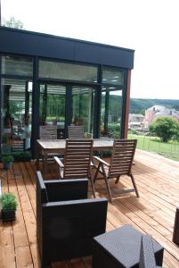 un patio con mesa y sillas en una terraza de madera en B&B Le Courtil en Dohan